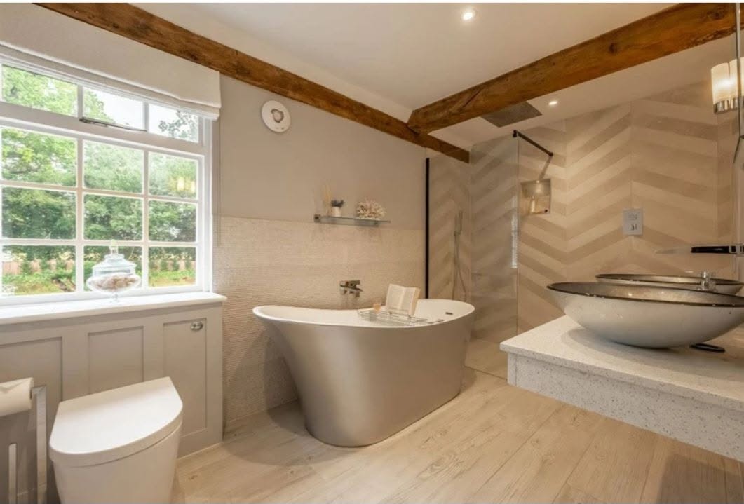 Bathroom with a freestanding bath, vessel basin and walk-in shower under exposed beams